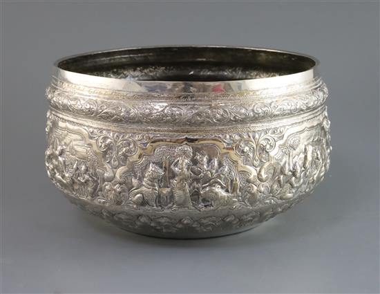 A Burmese silver rice bowl of large proportions with all round embossed scenes of figures, animals, scrolls and flowers,